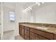 Bright bathroom featuring wood cabinets, granite countertops, double sinks, and vanity mirror at 13169 Bromborough Dr, Orlando, FL 32832