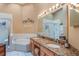 Bright bathroom featuring double sinks with granite countertops, soaking tub, and glass enclosed shower at 13209 Wild Duck Ct, Orlando, FL 32828