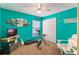 This colorful bedroom has turquoise walls, beach-themed decor, a ceiling fan, and an exercise bike for workouts at 13209 Wild Duck Ct, Orlando, FL 32828