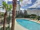 A beautiful swimming pool surrounded by deck chairs, mature palm trees, and nearby buildings at 155 S Court Ave # 2904-Penthouse, Orlando, FL 32801