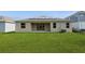 Well-manicured backyard features lush green grass, a covered patio, and solar panels on the roof at 1908 Perch Hammock Loop, Groveland, FL 34736