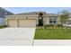 Well-manicured lawn and a beige stucco exterior with a three car garage give this house great curb appeal at 1908 Perch Hammock Loop, Groveland, FL 34736