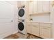 Well-lit laundry room featuring a stacked washer and dryer and custom cabinets for added storage at 1908 Perch Hammock Loop, Groveland, FL 34736