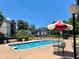 Community swimming pool with nearby seating and umbrella under a blue sky at 1932 Lake Atriums Cir # 77, Orlando, FL 32839