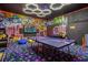 Vibrant game room showcases neon graffiti, ping pong, arcade machines, and modern hexagon lighting at 2560 Shanti Dr, Kissimmee, FL 34746