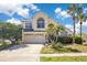 Charming two-story home featuring a two-car garage, arched windows, and lush landscaping with palm trees at 2806 Baywood Ln, Kissimmee, FL 34746