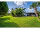 Expansive backyard featuring lush green grass, tropical foliage, and a charming patio area at 328 Lake Fair Ln, Winter Park, FL 32789