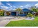 Charming blue home featuring a covered carport, well-manicured lawn, and tropical landscaping at 328 Lake Fair Ln, Winter Park, FL 32789