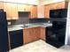 Well-lit kitchen featuring black appliances, granite countertops and wood finish cabinets at 335 Wymore Rd # 201, Altamonte Springs, FL 32714