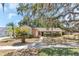 Exterior of a well-maintained tan home with mature trees and shrubs in the landscaped front yard at 3547 Medford Rd, Casselberry, FL 32707