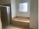 Bathroom with tiled floor, shower enclosure and large bathtub with tile surround and window at 415 Cinnamon Dr, Kissimmee, FL 34759