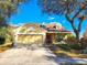 Charming yellow home with red front door, dormer windows, mature trees and a two-car garage at 4331 Willowcrest Ct, Orlando, FL 32826