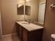 Bathroom showcasing a single sink vanity with a large mirror and a tiled floor at 602 Lochsmere Ln, Orlando, FL 32828