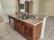 Kitchen island with stainless steel sink, granite countertop, dishwasher, and wooden cabinets at 602 Lochsmere Ln, Orlando, FL 32828