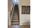 Carpeted staircase with wooden handrail, tile flooring, and decorative wall art at 602 Lochsmere Ln, Orlando, FL 32828