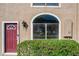 Close up of a townhome exterior featuring a red door, arched window, and green hedges at 606 Casa Park I Court, Winter Springs, FL 32708