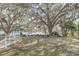 Scenic backyard showcasing mature trees, a lake view, and a white picket fence at 632 Tranquil Oaks Ln, Oviedo, FL 32765