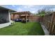 Outdoor pergola with seating area is set on lush artificial grass and surrounded by wood fencing at 7411 Golden Glenn Ct, Orlando, FL 32807