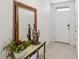 Bright and airy hallway with neutral tile floors, decorative mirror, and a white front door at 9537 Black Walnut Dr, Clermont, FL 34715