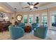 Bright living room with many windows features stylish turquoise armchairs, tan walls, ceiling fan and piano at 1112 Heron Point Way, Deland, FL 32724