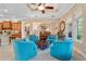 Bright living room features stylish turquoise armchairs, tan walls, ceiling fan, and kitchen view at 1112 Heron Point Way, Deland, FL 32724