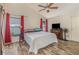 Cozy bedroom with wood-look floors, ceiling fan, and large windows with bright red curtains at 12972 Broakfield Cir, Orlando, FL 32837