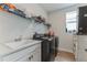 Functional laundry room with black washer/dryer, sink, white cabinets, and storage shelf above at 13819 Lanyard Way, Winter Garden, FL 34787