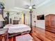 Spacious main bedroom with a four-poster bed, wooden floors, a ceiling fan, and ample storage with classic wood furniture at 1502 Hempel Ave, Windermere, FL 34786