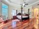 A relaxing main bedroom with hardwood floors, a four-poster bed, and soft, natural lighting from the large windows at 1502 Hempel Ave, Windermere, FL 34786