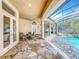 Covered patio with stone flooring, white columns, ceiling fans, and outdoor seating, leading to a screened pool at 1502 Hempel Ave, Windermere, FL 34786