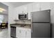 White kitchen with stainless steel appliances, gray countertops, and tile backsplash at 1982 Cricket Cradle Dr, Kissimmee, FL 34746