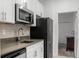 Well-lit kitchen featuring white cabinets, stainless steel appliances, gray counters and faucet at 1982 Cricket Cradle Dr, Kissimmee, FL 34746