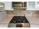 Close-up of a gas cooktop featuring granite countertops and white cabinets in the kitchen at 200 El Camino Dr # 402, Winter Haven, FL 33884