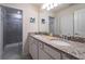 Bathroom with dual sinks, granite countertop and walk-in shower at 207 Jetty Way, Davenport, FL 33897