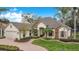 Beautiful single-story home features manicured lawn, stone accents, and brick-paved walkway to the entry at 210 Laurel Park Ct, Winter Park, FL 32792