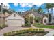 Charming front exterior features lush landscaping, stone accents, and a two-car garage, perfect for curb appeal at 210 Laurel Park Ct, Winter Park, FL 32792