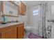 Bathroom featuring a vanity with storage, toilet, shower with a curtain and a window at 212 Glenn St, Leesburg, FL 34748