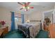 Well-lit bedroom with a dark iron bed frame, ceiling fan, and bright curtains at 212 Glenn St, Leesburg, FL 34748