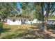 Spacious backyard featuring mature trees, a fence, and the exterior of the home at 213 James Dr, Winter Garden, FL 34787