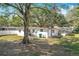 Large backyard with lots of mature trees, partial fencing, and the rear of the home at 213 James Dr, Winter Garden, FL 34787