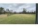 Large lawn area of the backyard surrounded by trees and shrubs and dark fencing at 2132 Limestone Trl, Kissimmee, FL 34747