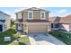 Home exterior featuring a two car garage, small garden, welcoming front door, and solar panels on the roof at 259 Southbridge Cir, Kissimmee, FL 34744