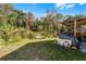 Backyard featuring a covered patio area with an unkempt lawn and bordered by vegetation at 2957 Birmingham Blvd, Orlando, FL 32829