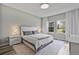 Bright, airy bedroom featuring a modern bed with gray accents, minimalist decor, and a window offering outdoor views at 4789 Terrace Bluff St, Winter Garden, FL 34787