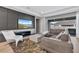 Modern living room with gray sofa, white chair, and a view to the outside through large windows at 4789 Terrace Bluff St, Winter Garden, FL 34787