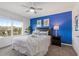 Comfortable bedroom with a blue accent wall, a bed with white linens and a large bright window at 5234 Wildwood Way, Davenport, FL 33837