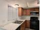Kitchen featuring wood cabinets, granite countertops, black appliances and stainless steel double sink at 5415 Fairwood Way # 303, Orlando, FL 32808