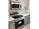 Modern kitchen appliances including a range and microwave in stainless steel with gray cabinetry at 6937 Se 23 Ave, Ocala, FL 34480