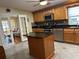 Well-equipped kitchen featuring a central island, wood cabinets, granite countertops, and stainless steel appliances at 723 Polo Park East Blvd, Davenport, FL 33897