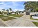 Exterior of a one-story home with a large driveway and well-manicured lawn at 7331 Blue Jacket W Pl, Winter Park, FL 32792